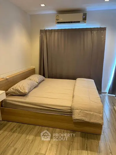 Cozy bedroom with wooden flooring and modern air conditioning unit, perfect for restful nights.