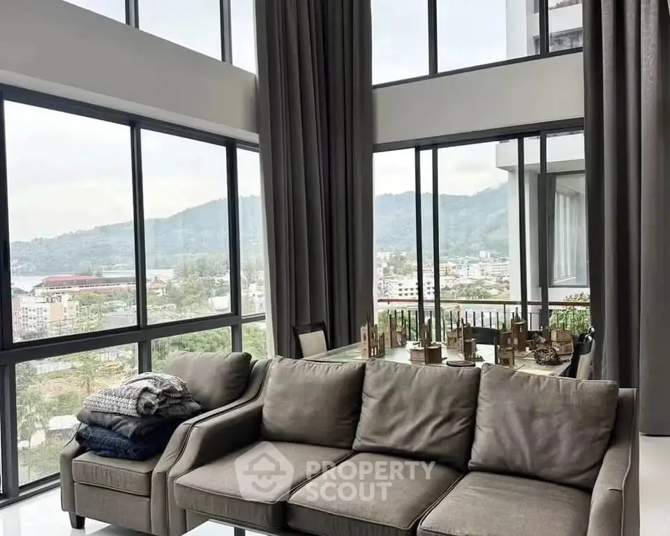 Luxurious living room with panoramic city and mountain views, featuring elegant decor and floor-to-ceiling windows.