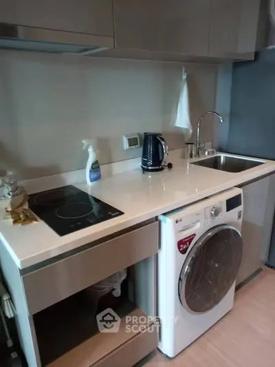 Modern kitchen with sleek appliances and compact design, featuring a washing machine and electric stove.