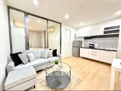 Modern open-layout living room with sleek kitchen, cozy sofa, and stylish decor in a bright apartment.