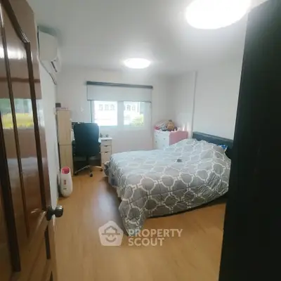 Cozy bedroom with modern decor and natural light, featuring a comfortable bed and work desk.