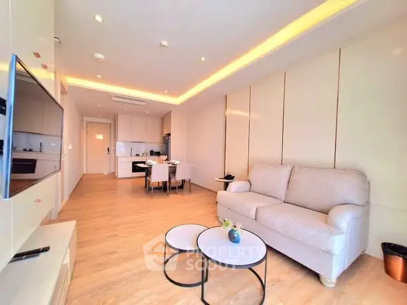 Modern living room with open kitchen, cozy sofa, and stylish lighting in a contemporary apartment.