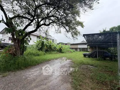 Spacious residential property with lush greenery and covered parking area.