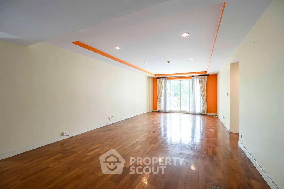 Spacious empty living room with wooden flooring and large windows