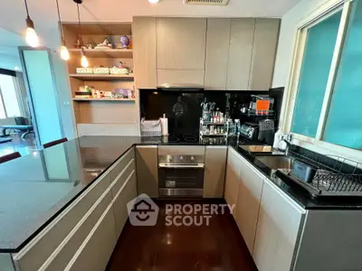 Modern kitchen with sleek cabinetry and built-in stainless steel appliances, featuring ample counter space and hardwood flooring.
