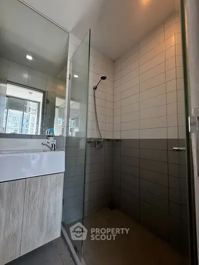 Modern bathroom with glass shower and sleek vanity in urban apartment.