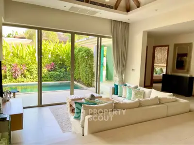 Luxurious living room with pool view, featuring elegant decor and large sliding glass doors opening to a lush garden.