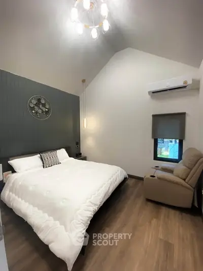 Modern bedroom with high ceiling, cozy armchair, and stylish decor
