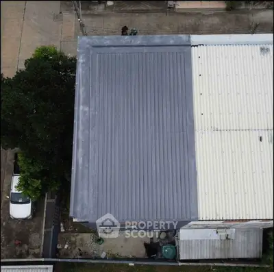 Aerial view of residential building with metal roof and adjacent parking area.