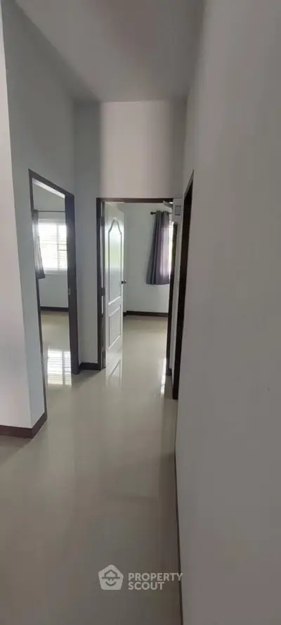 Spacious hallway leading to bright rooms with polished floors and modern design.