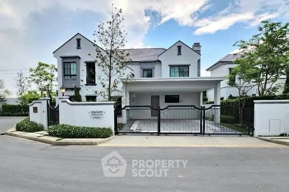 Elegant modern house with gated entrance and lush greenery, perfect for luxurious living.