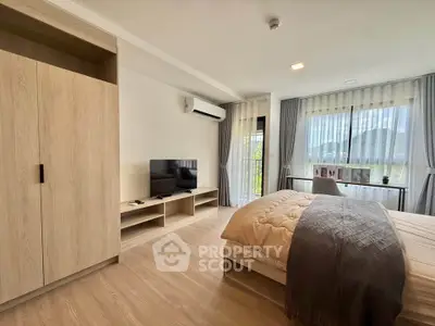 Spacious bedroom with modern decor, featuring a large window and stylish furnishings.