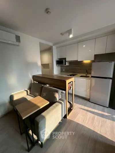 Modern kitchen with sleek design and integrated dining area, featuring stainless steel appliances.