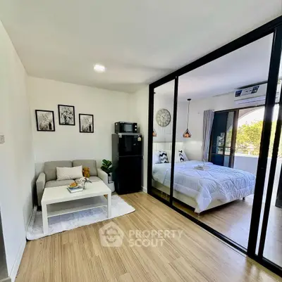 Modern studio apartment with glass partition, cozy living area, and stylish bedroom.
