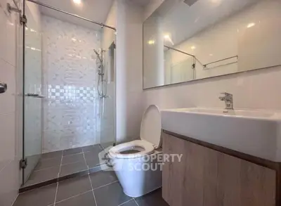 Modern bathroom with glass shower and sleek fixtures in contemporary apartment.