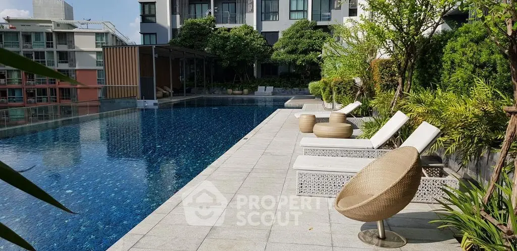 Luxurious apartment complex with stunning poolside area and modern outdoor seating.