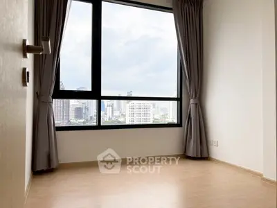 Spacious empty room with large window offering stunning city view, perfect for customization.