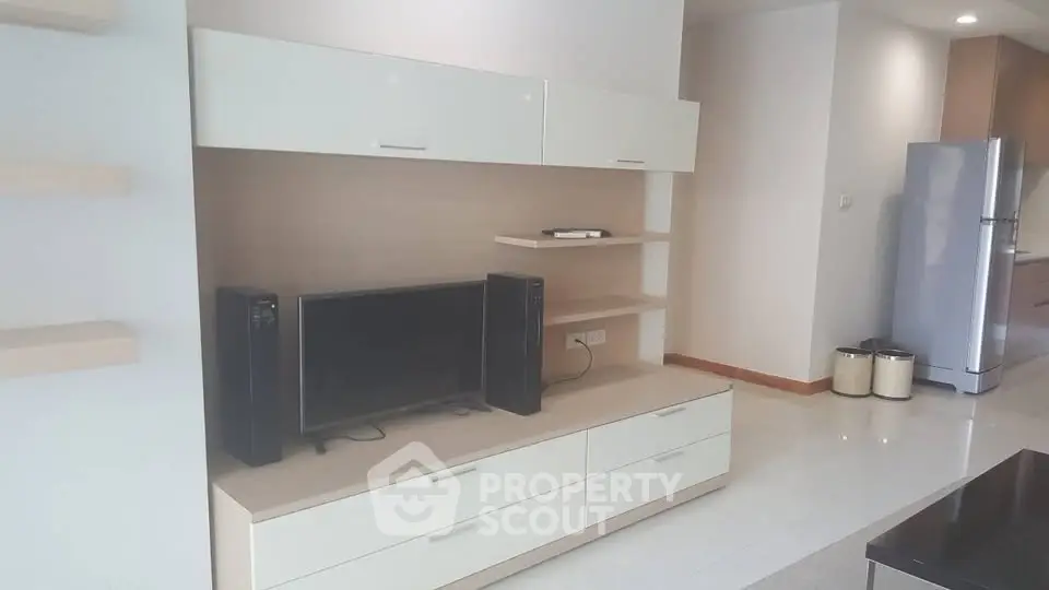 Modern living room with sleek entertainment unit and contemporary kitchen appliances.