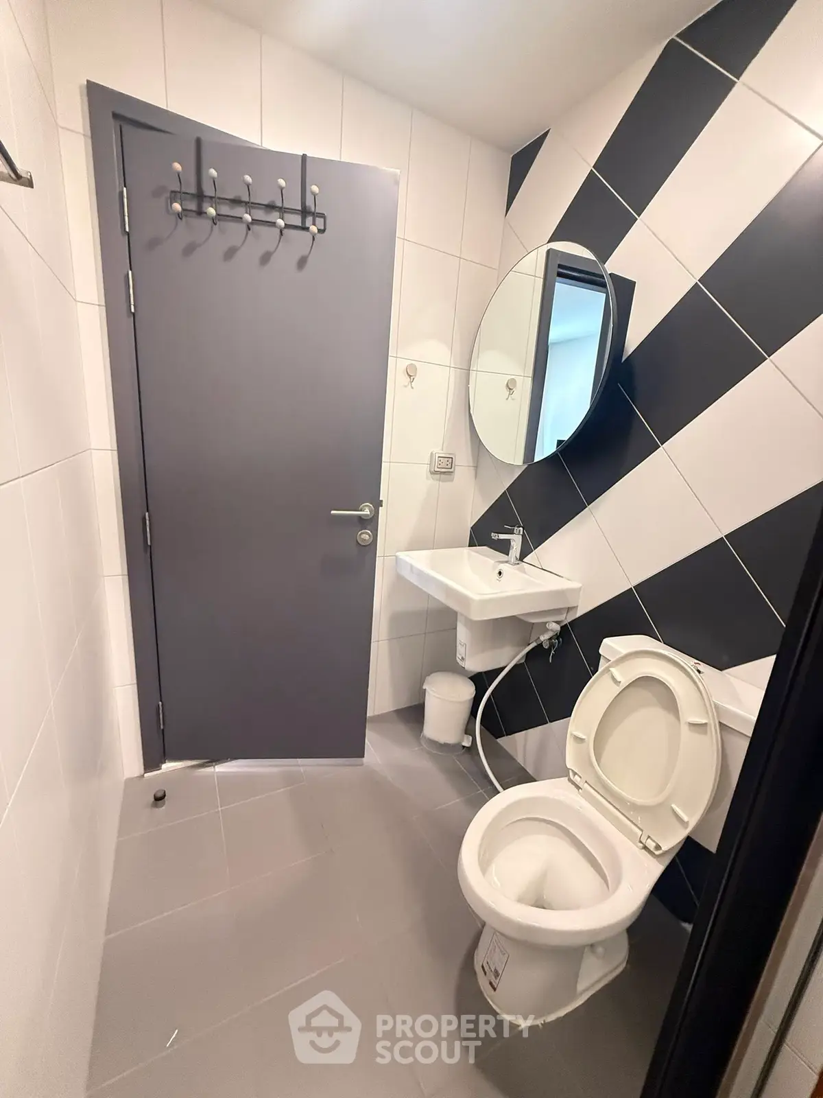 Modern bathroom with sleek design, featuring a round mirror and stylish black and white tiles.