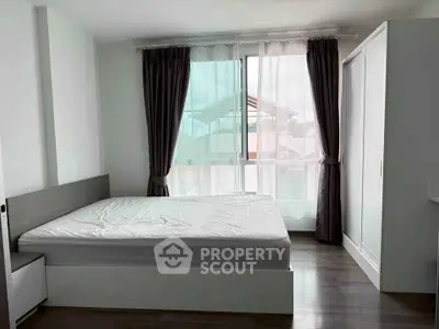 Spacious bedroom with large window and modern furnishings in a stylish apartment.
