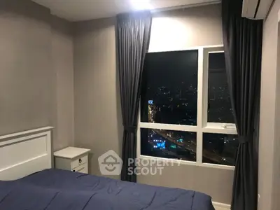 Cozy bedroom with city view, featuring elegant curtains and modern decor, perfect for urban living.