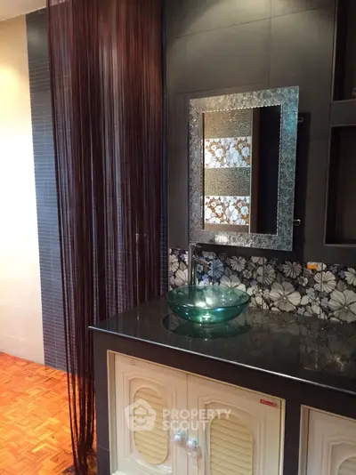 Stylish bathroom with glass sink and floral tile backsplash