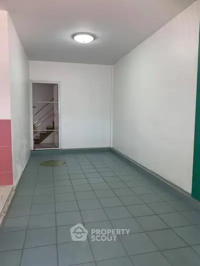 Spacious tiled hallway with stairway access in modern building