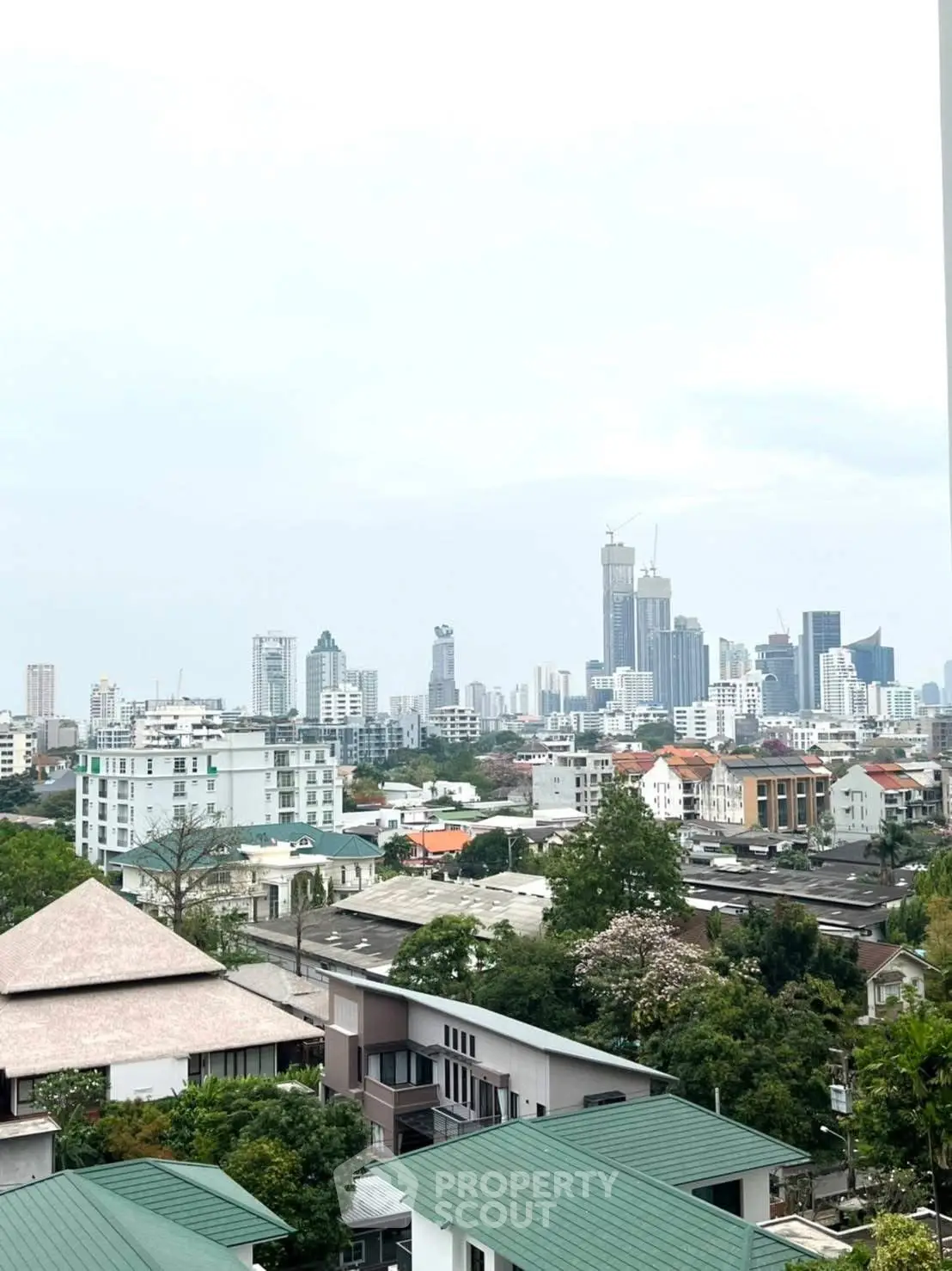 Stunning cityscape view from a high-rise building, showcasing urban skyline and lush greenery.