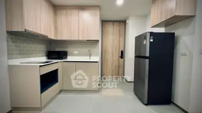 Modern kitchen with sleek cabinetry and stainless steel fridge in cozy apartment.