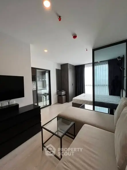 Modern studio apartment with open layout, featuring sleek furniture and large windows for natural light.