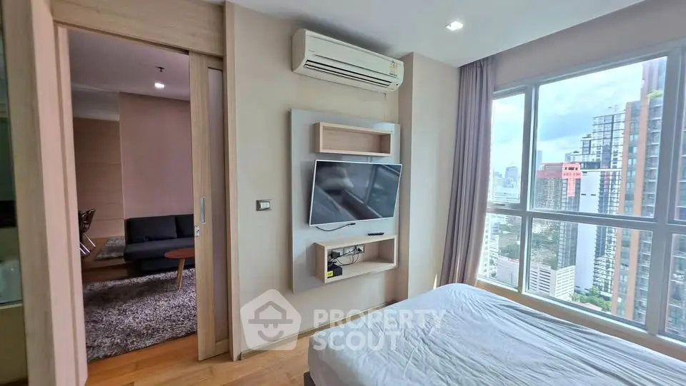 Modern bedroom with city view and wall-mounted TV in a high-rise apartment