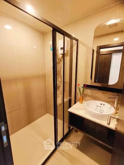 Modern bathroom with sleek shower enclosure and stylish vanity in contemporary apartment.