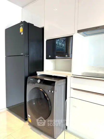 Modern kitchen with sleek appliances including fridge and washing machine, perfect for contemporary living.
