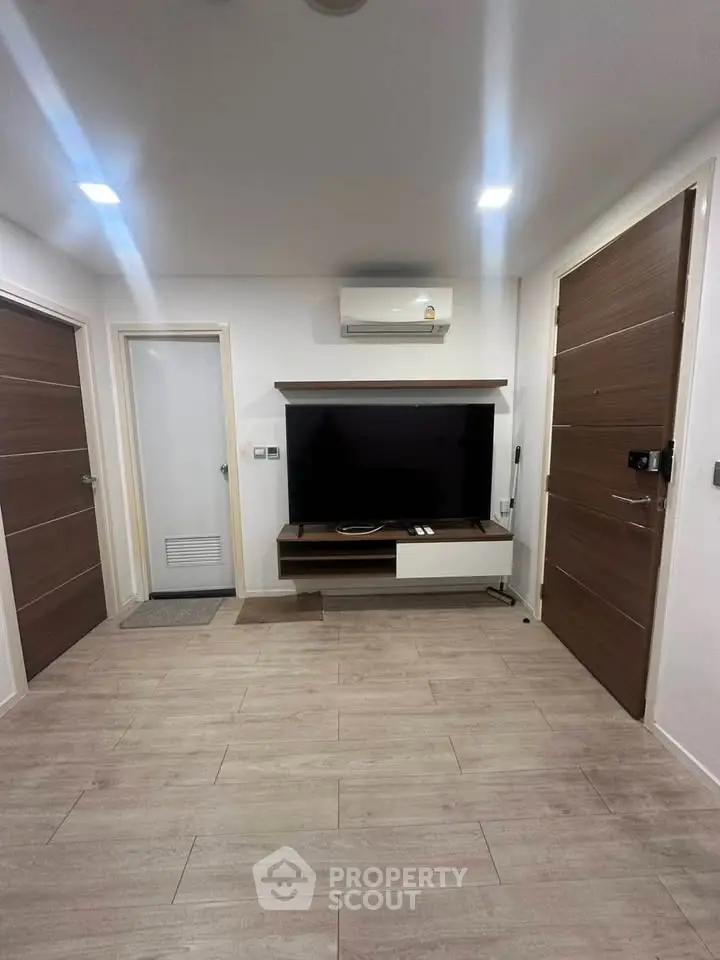 Modern living room with sleek wooden flooring and wall-mounted TV unit.