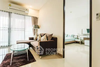 Modern living room with cozy sofa and glass coffee table, adjacent to a bright bedroom with stylish decor.