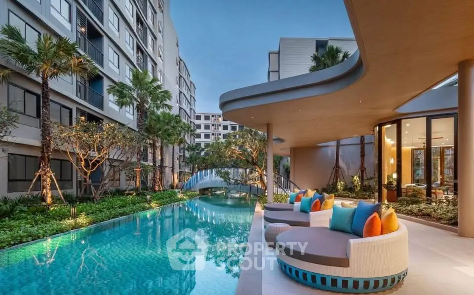 Luxurious apartment complex with stunning pool and modern outdoor seating area.