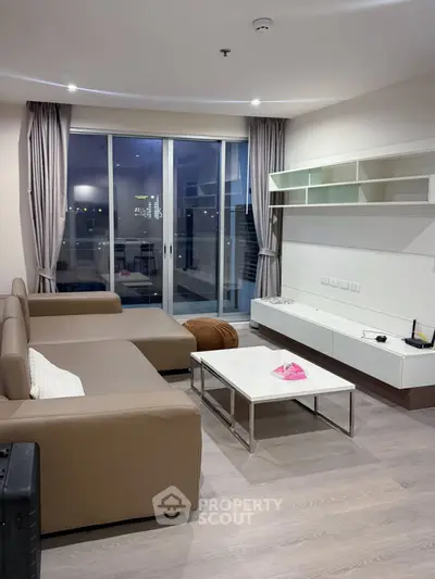 Modern living room with sleek furniture and large windows offering city views.