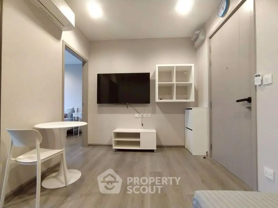 Modern living room with minimalist furniture and wall-mounted TV in a cozy apartment.