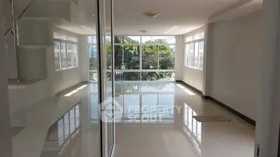 Spacious and bright living room with large windows and glossy floors.