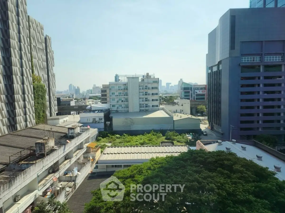 Stunning urban view from high-rise building showcasing city skyline and lush greenery.