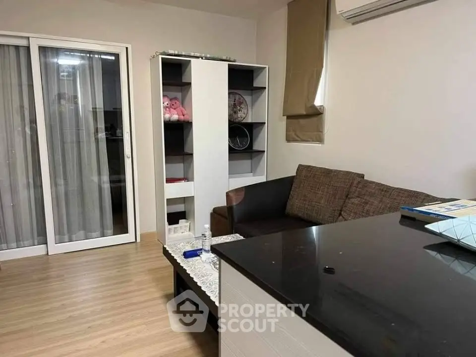Cozy living room with modern decor and air conditioning, featuring a comfortable sofa and stylish shelving unit.