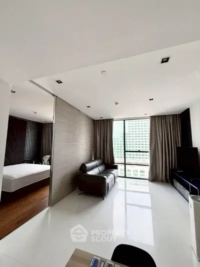 Modern apartment with sleek living room and bedroom, featuring large windows and contemporary design.