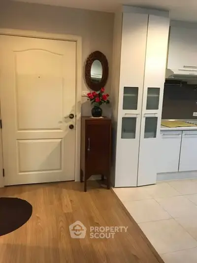 Charming entryway with modern kitchen view, featuring sleek cabinets and stylish decor.