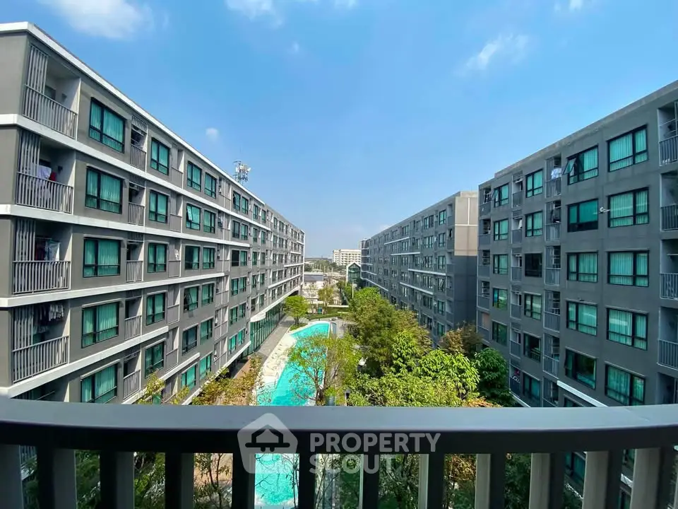 Modern apartment complex with pool view and lush greenery under a clear blue sky.
