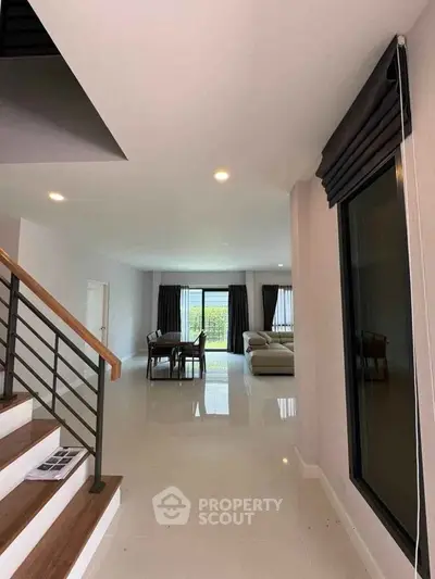 Spacious modern living room with elegant staircase and large windows