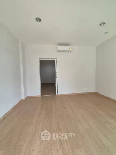Spacious empty room with wooden flooring and air conditioning, ideal for customization.