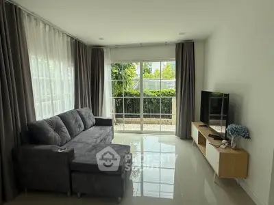 Spacious living room with large windows and modern furniture, offering a bright and inviting atmosphere.
