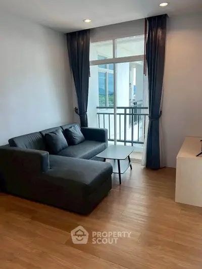 Modern living room with sleek sofa and balcony view, perfect for relaxation and enjoying natural light.