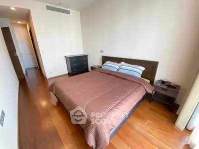 Spacious bedroom with wooden flooring and modern furniture in a stylish apartment.