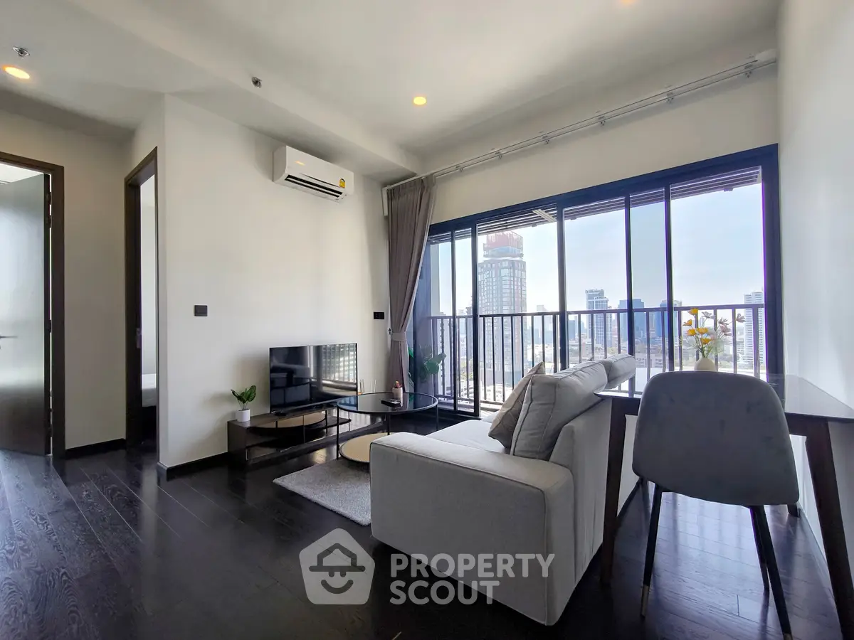 Modern living room with city view, featuring sleek furniture and large windows for natural light.